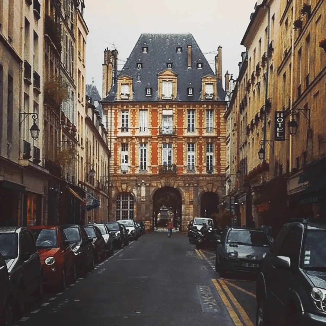A Parisian street receding toward a grand historic building under an overcast sky