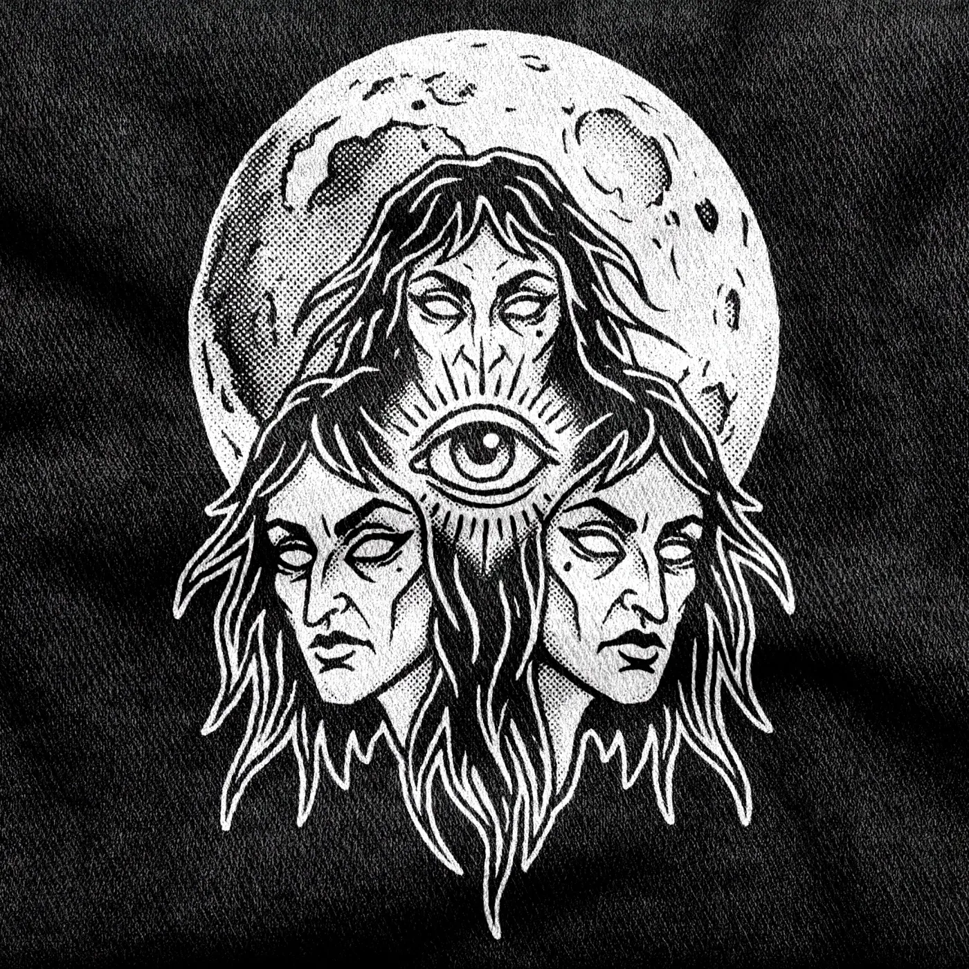 Three faces around a central staring eye under a full moon, the Three Mothers witch-trilogy emblem, white on a black tee.
