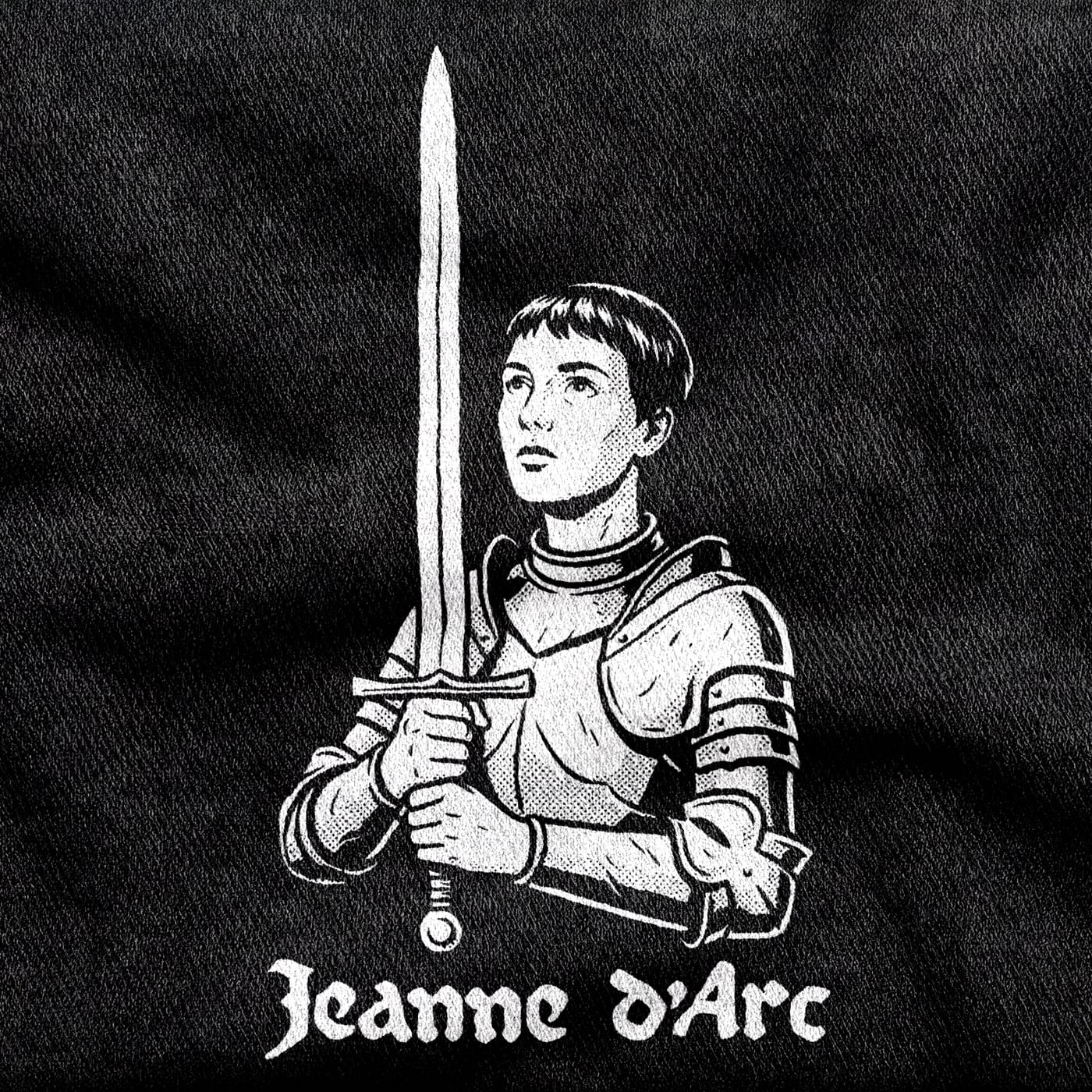 Joan of Arc in plate armour with cropped hair, her sword held upright like a cross, under a blackletter wordmark, white on a black tee.