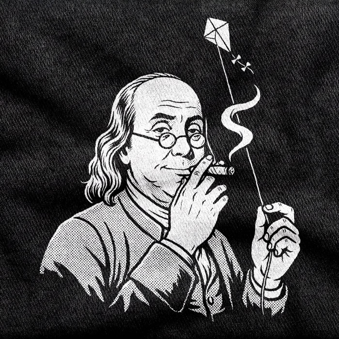 Benjamin Franklin in spectacles and a colonial coat, a kite string in one hand and something rolled and lit in the other, white on a black tee.