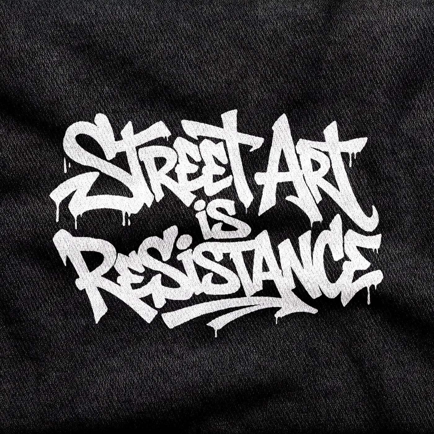 Marker handstyle with running drips reading "Street Art is Resistance", white on a black tee.