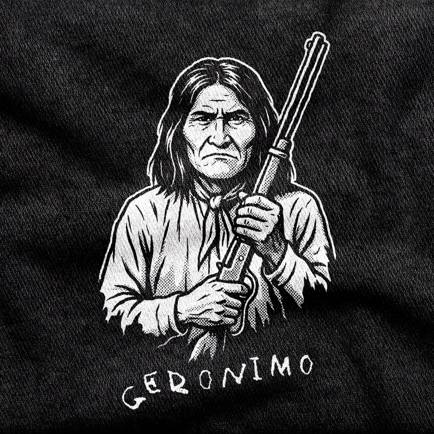 The Chiricahua Apache leader Geronimo holding a lever-action rifle upright, neckerchief at his throat, above his handwritten signature, white on a black tee.