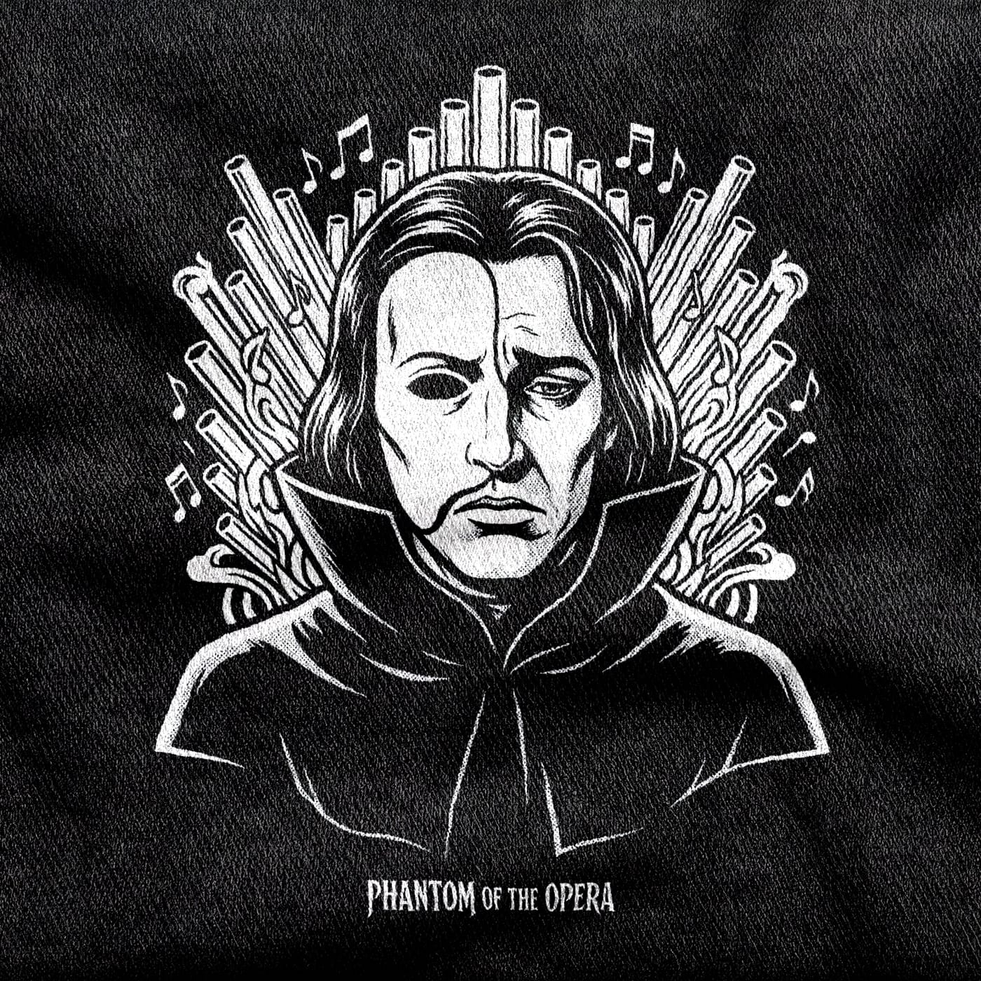 The Phantom of the Opera in a cape with half his face in shadow, backed by a fan of organ pipes and drifting notes, white on a black tee.