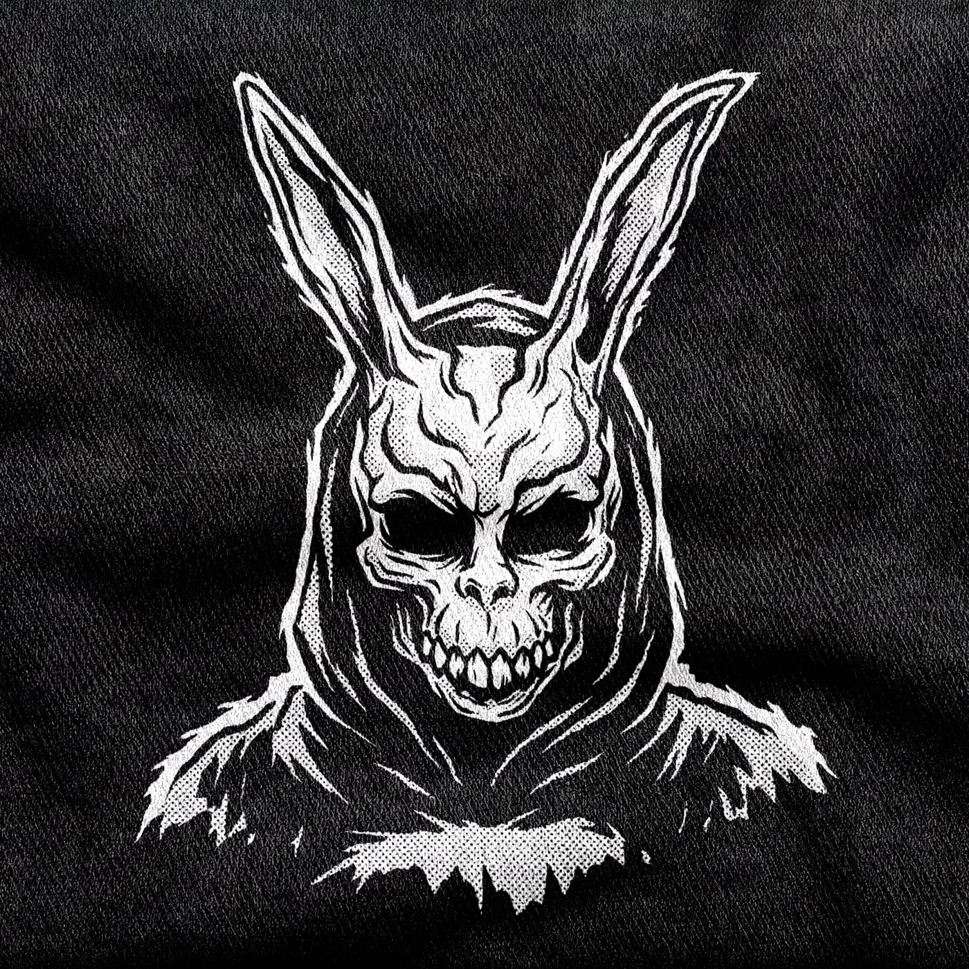 The Donnie Darko rabbit mask alone, hollow-eyed with a jagged grin, white on a black tee.