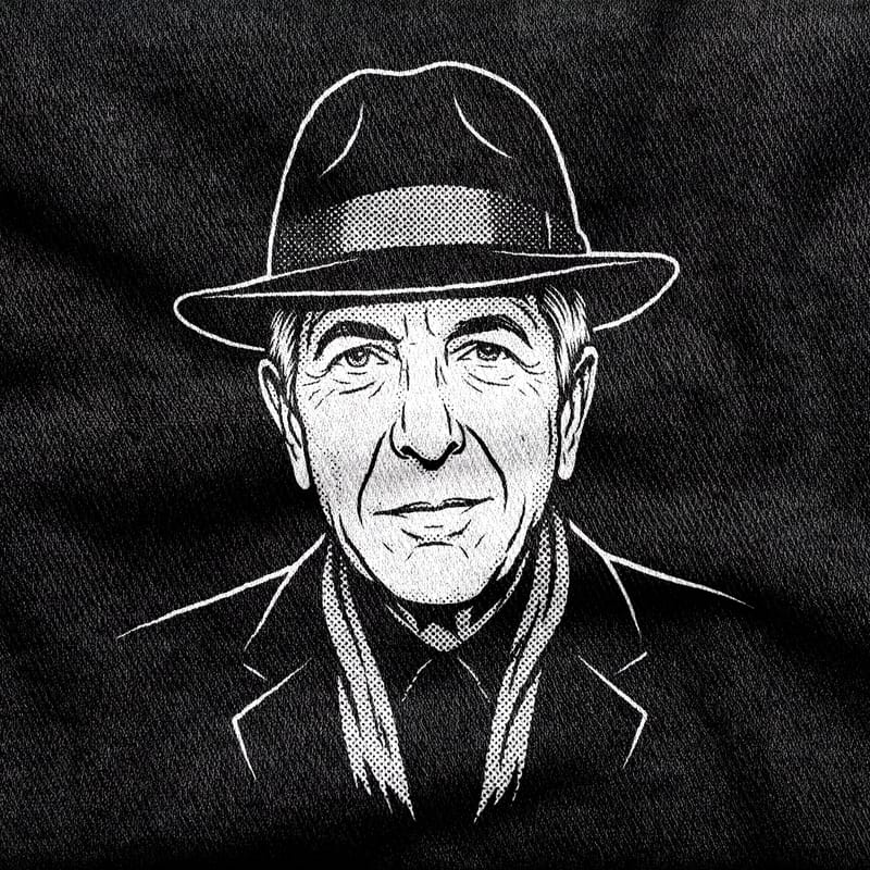 A portrait of Leonard Cohen in fedora, scarf and suit, his face deeply lined, white on a black tee.