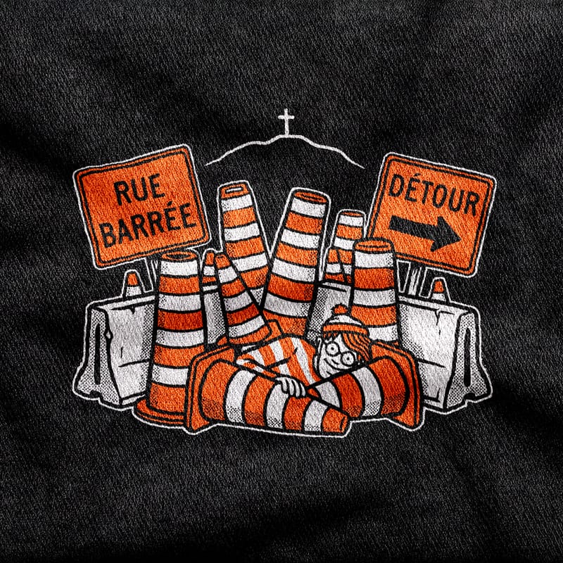 Orange cones and barriers under "Rue barrée" and "Détour" signs, Waldo's striped hat hidden among them and the Mount Royal cross on the skyline, white and orange on a black tee.
