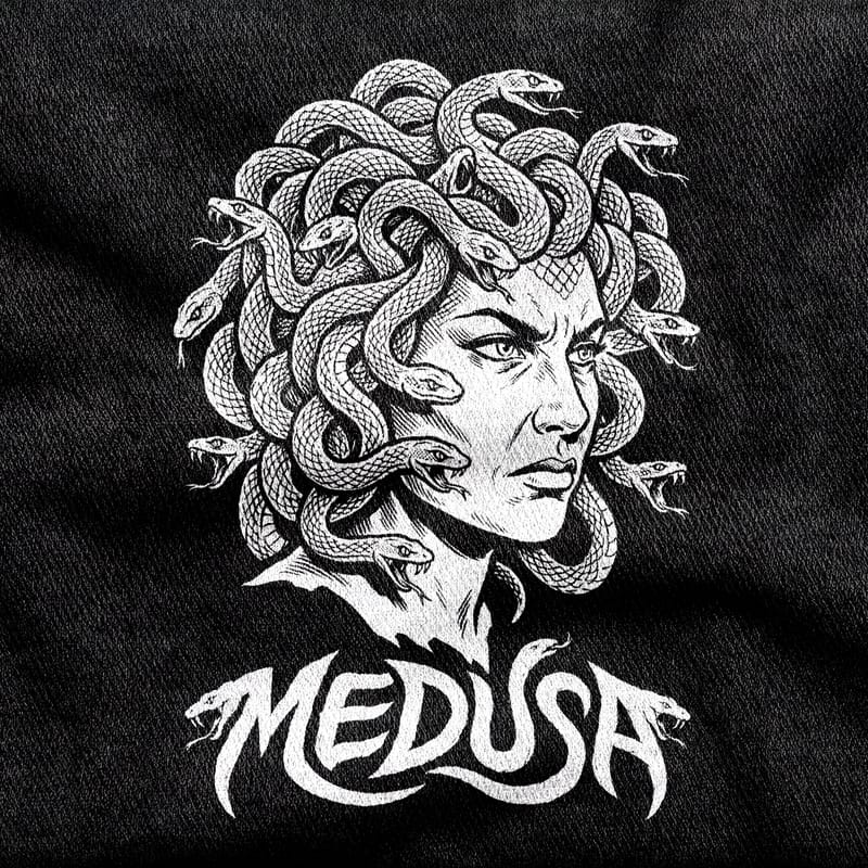 Medusa's grieving, angry face under a crown of coiling snakes, with a wordmark whose letters taper into snake heads, white on a black tee.
