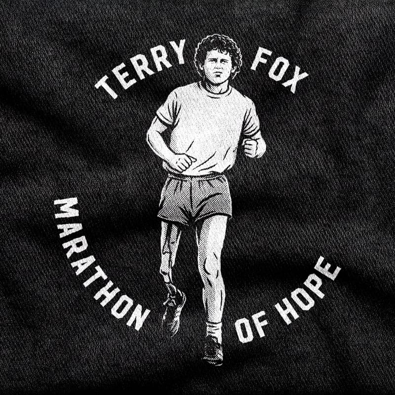 Terry Fox mid-stride on his prosthetic leg, ringed by the words "Marathon of Hope", white on a black tee.