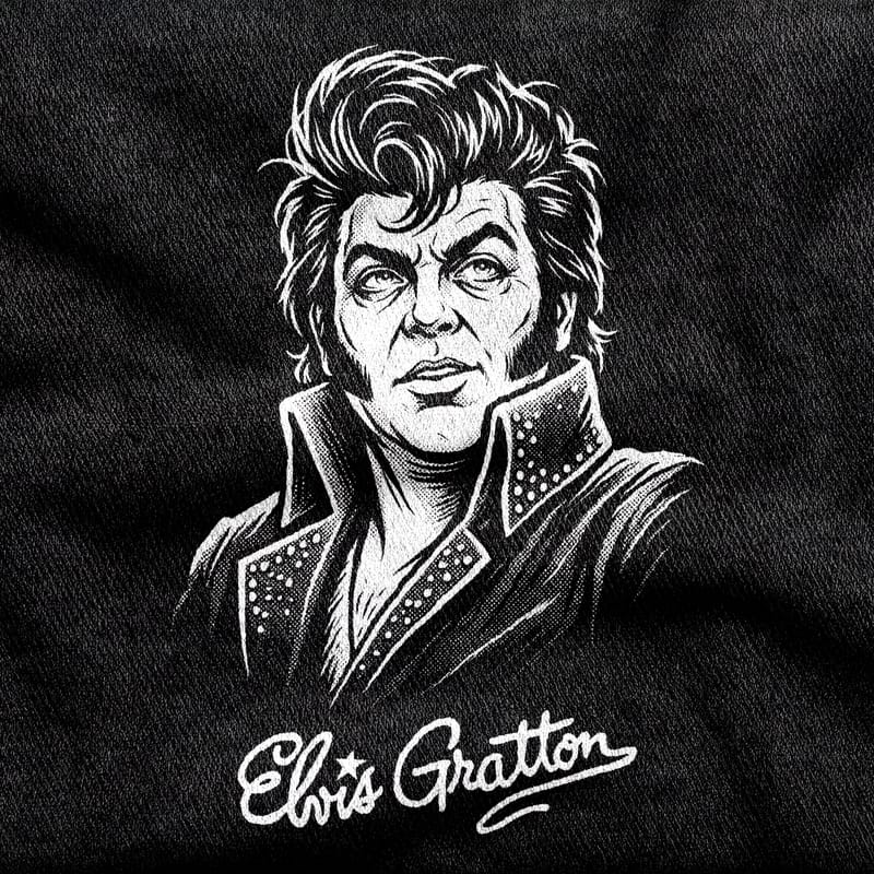 Elvis Gratton with his pompadour, jowls and rhinestone-studded collar, over a signature-style wordmark, white on a black tee.