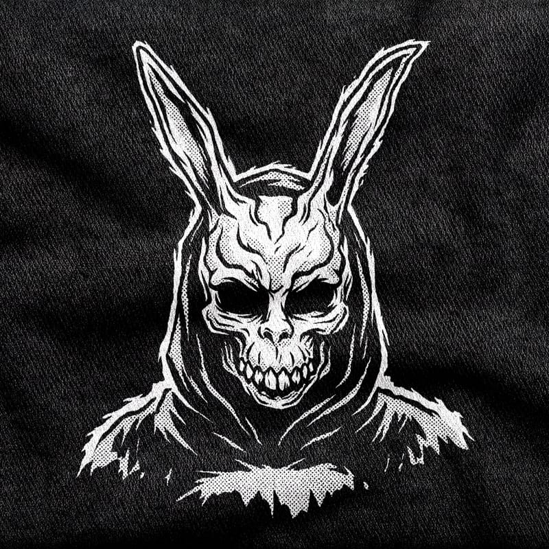 The Donnie Darko rabbit mask alone, hollow-eyed with a jagged grin, white on a black tee.